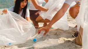 Asian young happy family activists collecting plastic waste on beach.